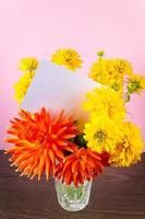 tarjeta de felicitación en blanco en ramo de flores de verano amarillas sobre fondo rosa. invitación de vacaciones, lugar para texto. foto