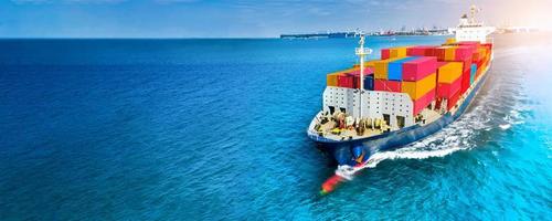 Aerial side view of cargo ship carrying container and running on blue sea for export  goods  from  cargo yard port to custom ocean concept technology transportation , customs clearance. photo