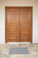 Wooden door with door mat on tiled floor photo