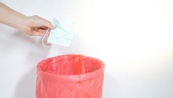 Female throw surgical mask after use throwing  in dangerous trash to prevent virus from spreading from mask to trash can and to people. photo