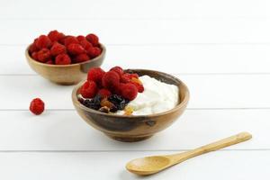 Yogurt in Wooden Bowl with Spoons, Healthy Breakfast with Fresh Greek Yogurt and Raspberry on Background. photo