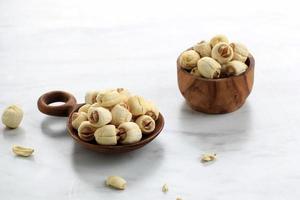 Dried Lotus Seed on Wooden Spoon above White Table