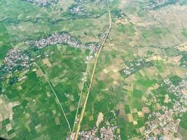 el paisaje aéreo muestra una vista verde de la ciudad. calles, campos de arroz y casas de pueblo. foto