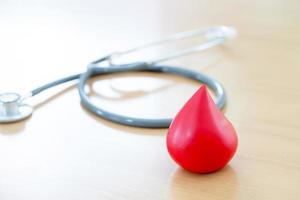 Stethoscope and a red blood  put on wooden photo