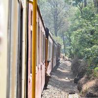 Toy Train moving on mountain slopes, beautiful view, one side mountain, one side valley moving on railway to the hill, among green natural forest. Toy train from Kalka to Shimla in India photo