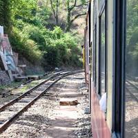 Toy Train moving on mountain slopes, beautiful view, one side mountain, one side valley moving on railway to the hill, among green natural forest. Toy train from Kalka to Shimla in India photo