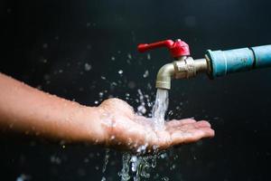 Good water management ideas make us have water to use forever. faucet with running water On a black background there is a copy space. photo