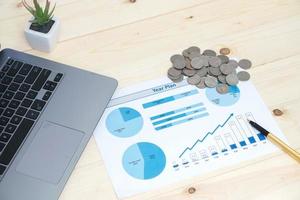Coins stacks with notebook laptop computer and financial graph photo
