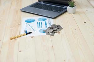 Coins stacks with notebook laptop computer and financial graph photo