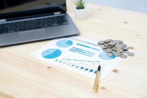 Coins stacks with notebook laptop computer and financial graph photo
