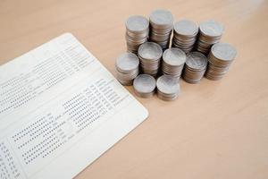 ahorrar dinero con pila de monedas y libreta en mesa de madera foto
