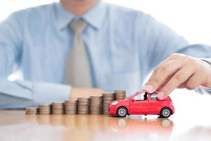 Person Holding Car Over Rising Stacked Coins photo