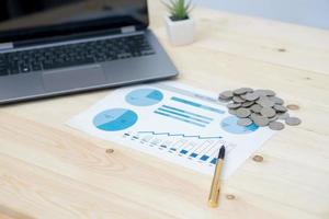 Coins stacks with notebook laptop computer and financial graph photo