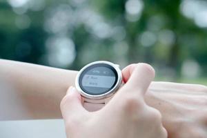 Woman running outdoors using watch photo