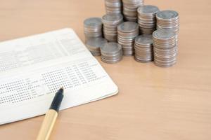 monedas y bolígrafo en la libreta de la cuenta de ahorros foto