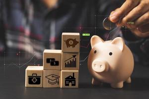 Hand puting coin on piggy bank and stacking wood block.money saving concept photo