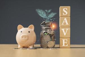 piggy bank with coin and leaves on wooden table, saving money concept photo
