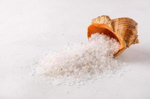 Organic spa sea salt is poured into a pile and a shell from the sea photo