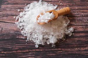 Flower of salt, is a salt that forms as a thin, delicate crust on the surface of seawater in the wooden scoop on wooden background. photo