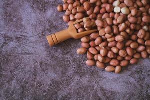 Raw Groundnuts on cement background with wooden scoop. Top view. copy space for text. photo