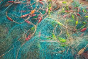 Sea nets - fishing equipment or tackle as texture backdrop with natural sunlight and shadow. Blue textured background of fishing nets close-up, marine design for craft of fishermen. photo