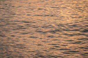 Sunset water reflect ripples at sun light. Abstract golden reflection on water sunset photo