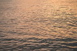 Sunset water reflect ripples at sun light. Abstract golden reflection on water sunset photo