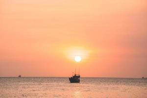 Tropical Seascape with a boat on sandy beach at cloudy sunrise or sunset. Beautiful sunset tropical beach with small boat and cinematic sky for travel and vacation in holiday relax time. photo