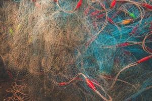 Sea nets - fishing equipment or tackle as texture backdrop with natural sunlight and shadow. Blue textured background of fishing nets close-up, marine design for craft of fishermen. photo