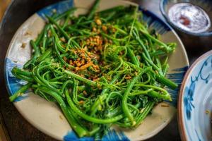 Focus on stir fried sweet potato leaves with garlic, vietnamese cuisine. Traditional Meal in Country side. photo