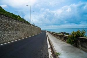 destino perfecto para un viaje por carretera durante la puesta de sol en una isla de vietnam. hai largo costero panorámico con olas, costa, cielo despejado y carretera, mar azul y montaña. foto