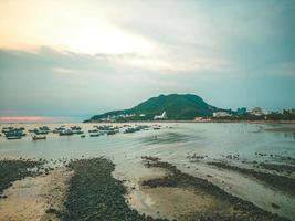 Vung Tau city aerial view with beautiful sunset and so many boats. Panoramic coastal Vung Tau view from above, with waves, coastline, streets, coconut trees and Tao Phung mountain in Vietnam. photo