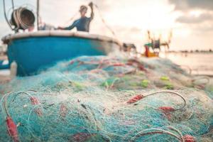 Sea nets - fishing equipment or tackle as texture backdrop with natural sunlight and shadow. Blue textured background of fishing nets close-up, marine design for craft of fishermen. photo