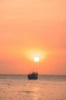 Tropical Seascape with a boat on sandy beach at cloudy sunrise or sunset. Beautiful sunset tropical beach with small boat and cinematic sky for travel and vacation in holiday relax time. photo