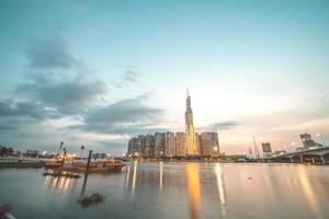 ciudad de ho chi minh, vietnam, 11 de febrero de 2022 vista de la puesta de sol en el punto de referencia 81: es un rascacielos súper alto y un puente de saigón con edificios de desarrollo a lo largo del río saigón, la luz se suaviza foto