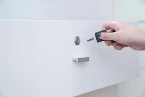 women hand holding the black simple key to open the white wardrobe. Clear background. photo