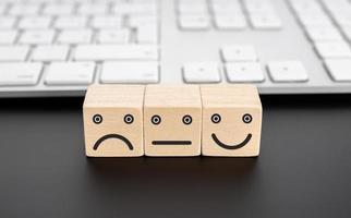 User service feedback, rating and customer review concept. Wooden blocks with facial expression icon and computer keyboard photo