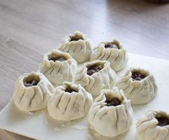 The process of making home-made dumplings. Raw homemade dumplings on a wooden board. Molding dumplings. photo