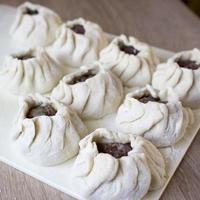 The process of making home-made dumplings. Raw homemade dumplings on a wooden board. Molding dumplings. photo