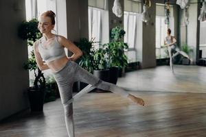 Athletic slender red haired woman during her fitness workout with rubber resistance band photo