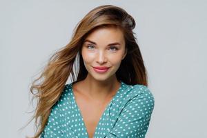 el retrato de una hermosa joven tiene maquillaje, se viste con una camisa de lunares, trabaja como modelo de moda posa sobre fondo blanco, usa lápiz labial, tiene una piel suave y saludable. expresiones faciales foto