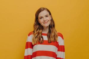 Lovely and cute teen girl feeling happy and satisfied while posing isolated over yellow background photo