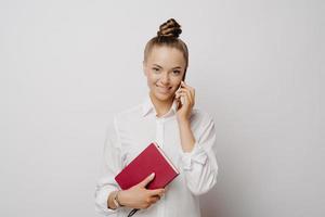 joven mujer de negocios hablando por teléfono y sintiéndose satisfecha con los resultados del trabajo foto