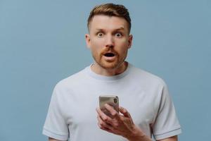 Surprised man reading unexpectable news on mobile phone photo