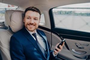 Corporate executive in elegant expensive tuxedo rides in luxury car photo
