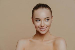 hermosa niña sonriente con piel limpia, maquillaje natural y dientes blancos sobre fondo beige. moda, belleza, maquillaje, cosmética. foto