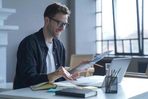 Young German businessman in glasses discussing calculation chart reports with partners online photo