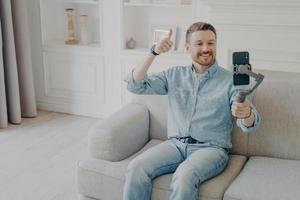 Young man showing thumbs up gesture on camera on mobile phone photo