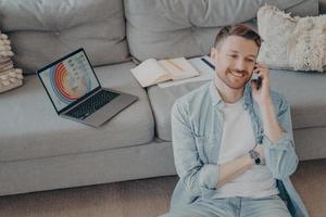 Happy young man calling family to inform about receiving promotion photo