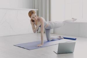 Woman coach has video class. Young athlete practicing yoga. Personal training by video lessons. photo